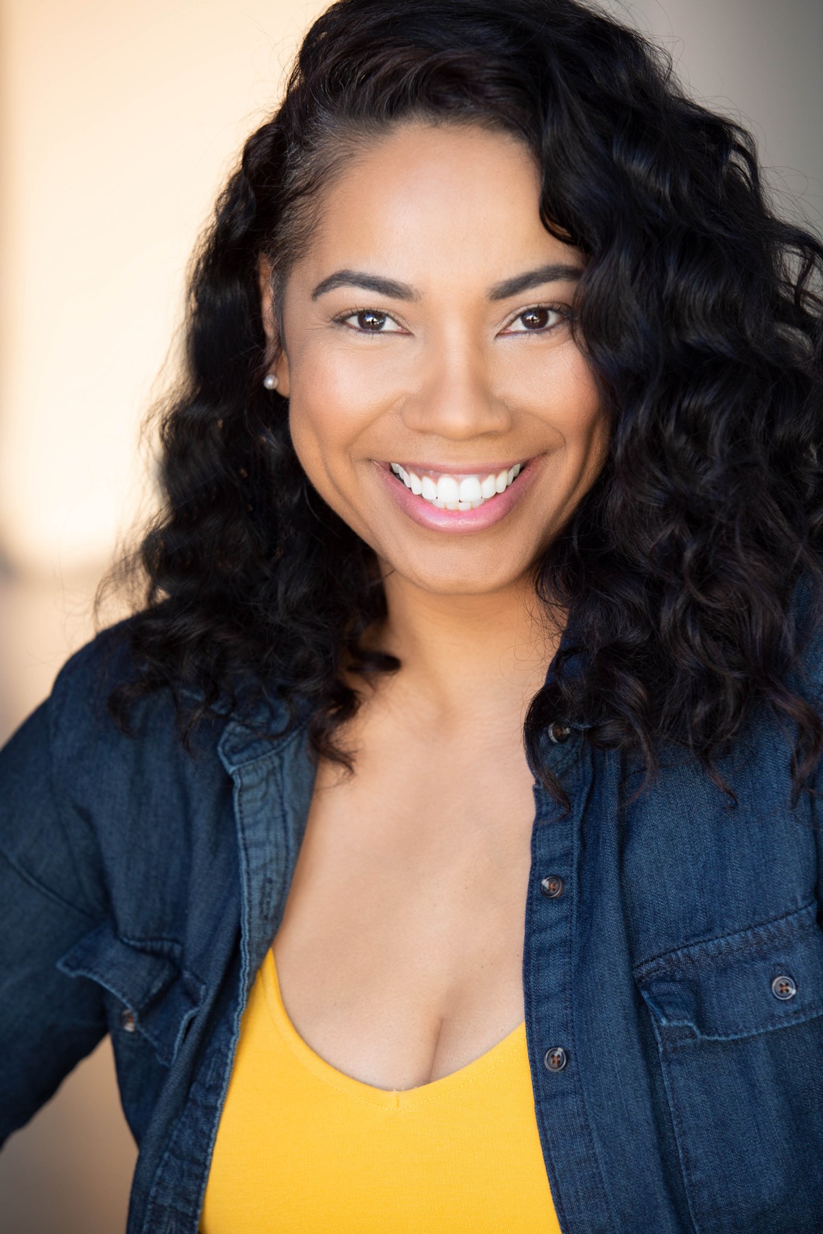 Mignon Farmani smiling in a denim shirt and yellow top